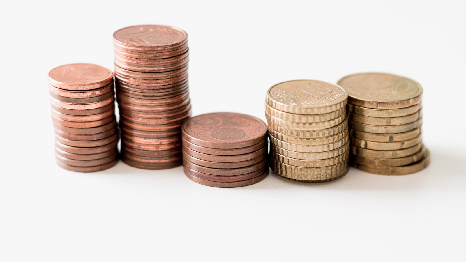 Stacked gold-colored coins on a white surface — alternatives to European bank savings that beat 2% deposit rates in 2026.